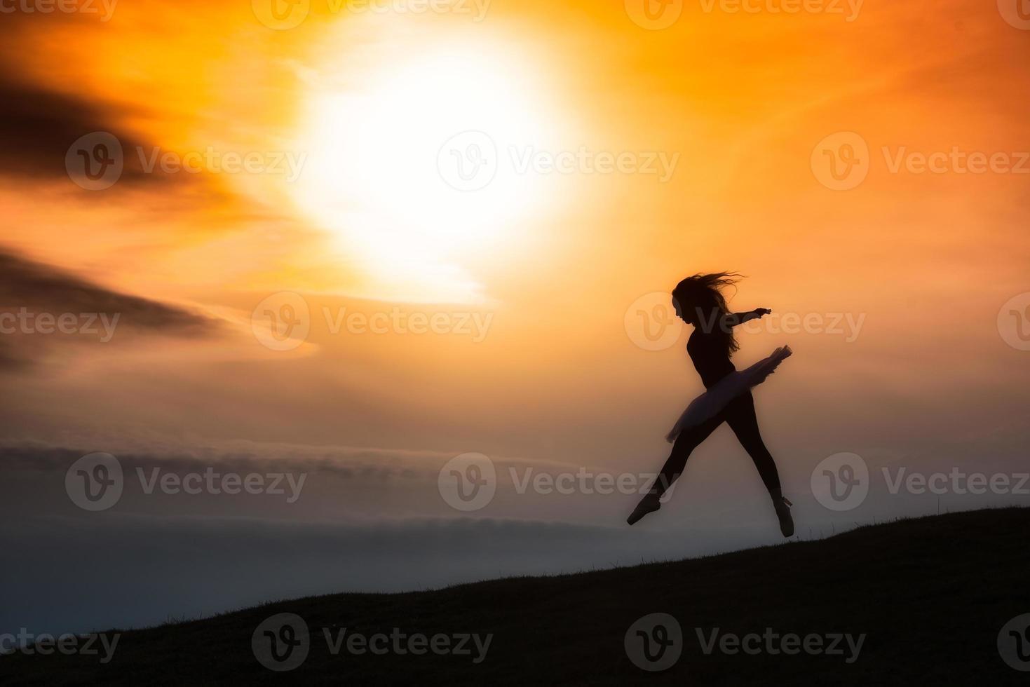 Ballerina silhouette, dancing alone in nature in the mountains at sunset photo
