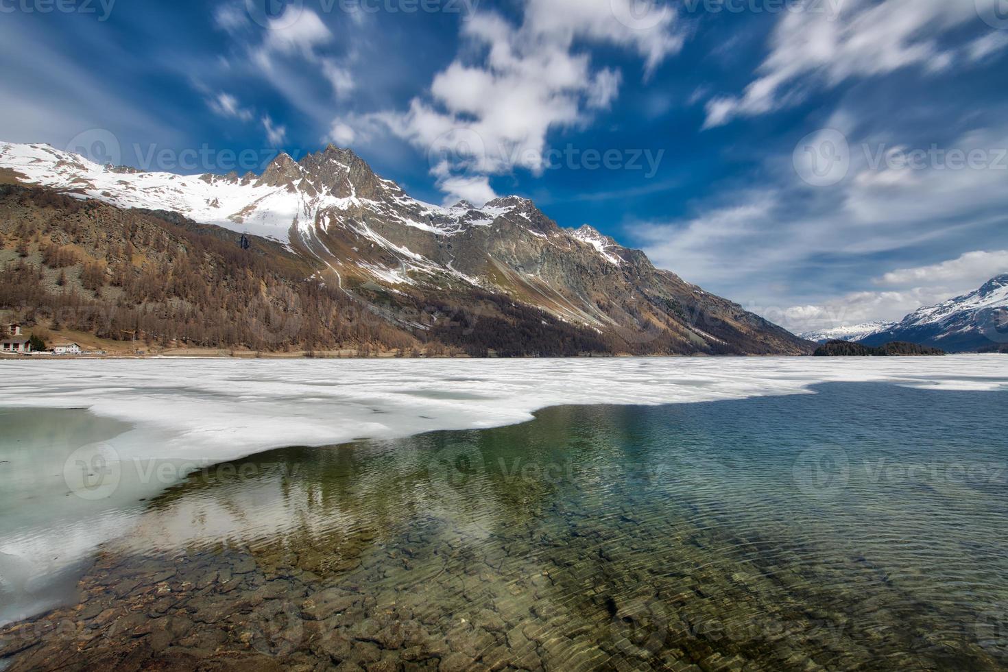 Mountain landscape in the Engadine valley with a play of lights at the thaw of the lake photo