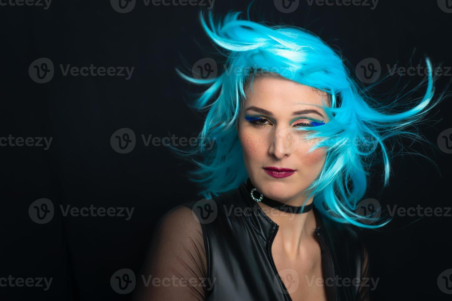 A girl on a black background with blue wig and hair in the wind photo