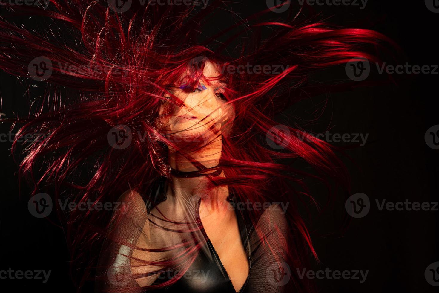 A girl on a black background with double exposure with red hair in the wind photo