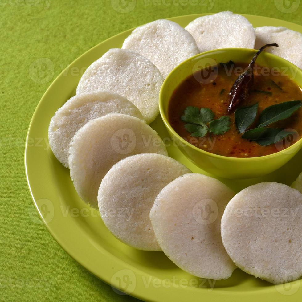 Idli with Sambar in bowl on green background, Indian Dish south Indian favourite food rava idli or semolina idly or rava idly, served with sambar and green coconut chutney. photo