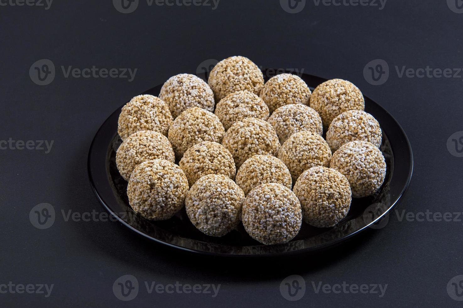 amaranto ladoo o rajgira laddu o cholai ke laddo en placa negra sobre fondo negro. foto