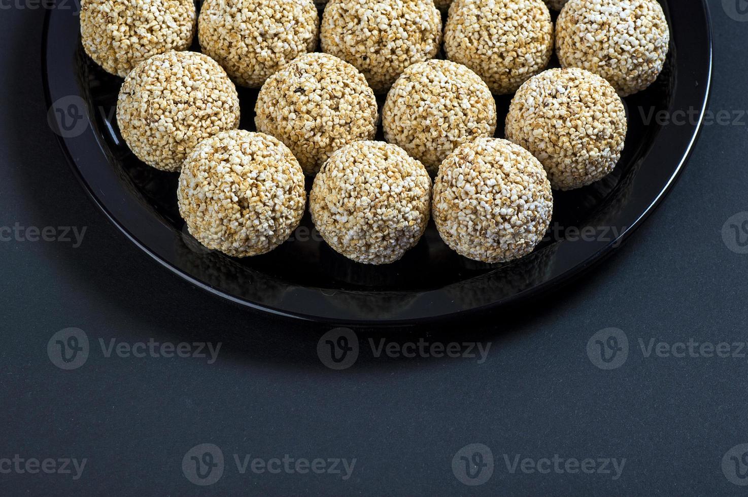 amaranto ladoo o rajgira laddu o cholai ke laddo en placa negra sobre fondo negro. foto