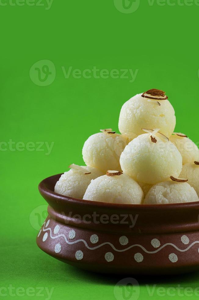 Dulce indio o postre - rasgulla, famoso dulce bengalí en cuenco de arcilla sobre fondo verde foto