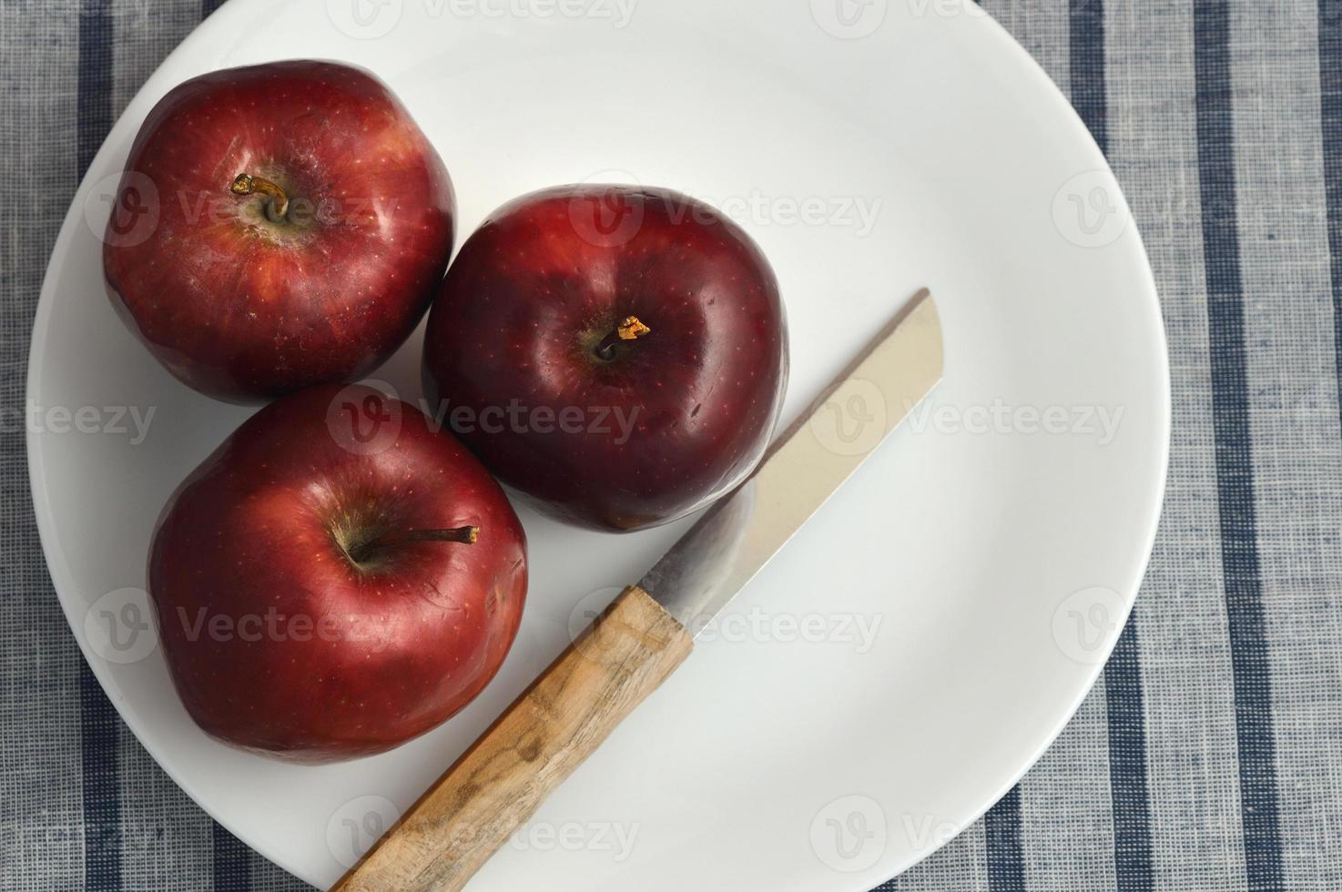 Deliciosas manzanas en un plato con un cuchillo sobre un mantel rayado foto