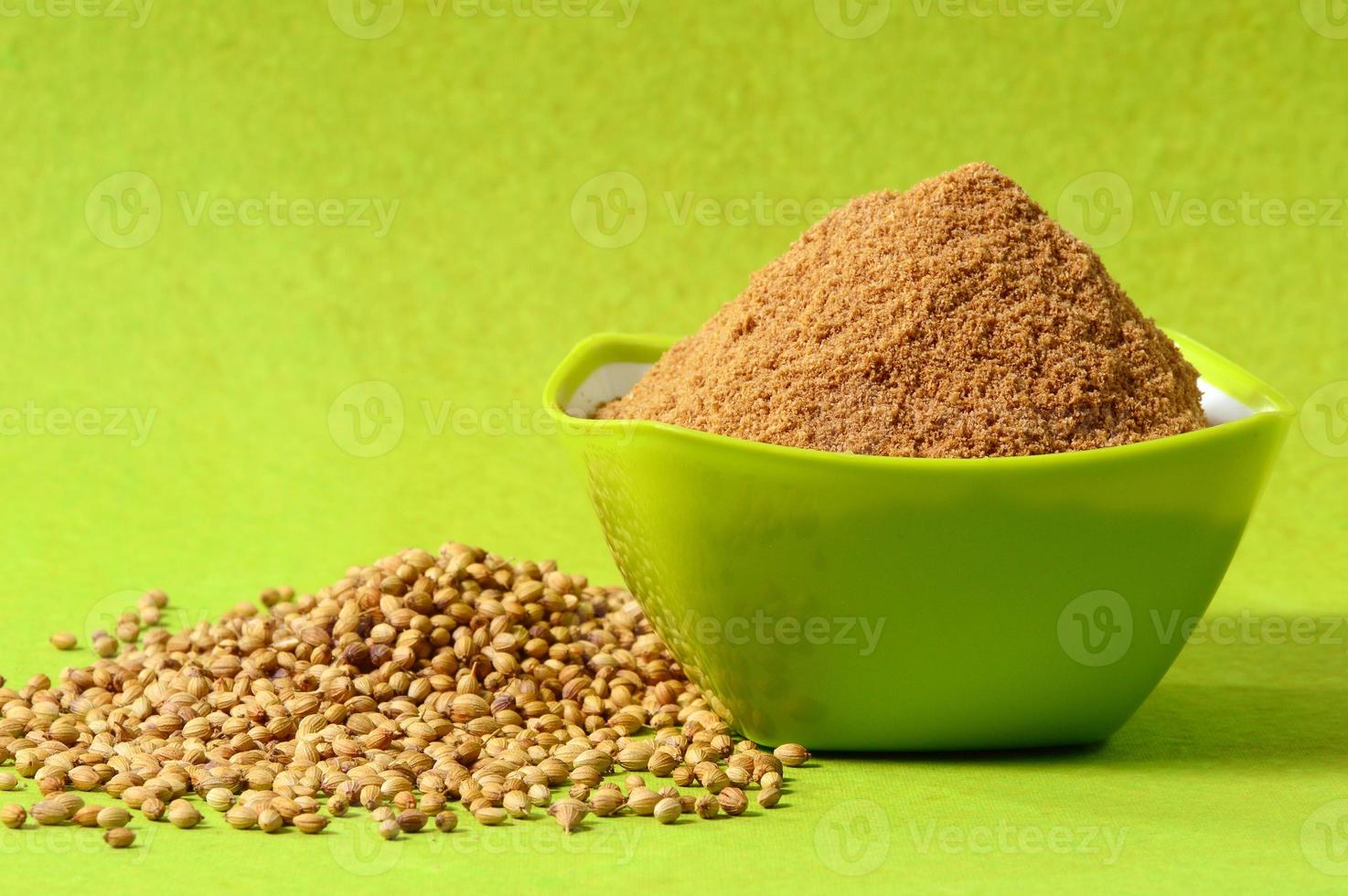 Coriander seeds and Powdered coriander in green container on green background photo