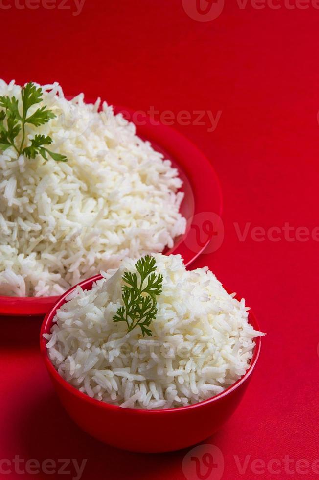 arroz basmati blanco liso cocido en un tazón y plato sobre fondo rojo. foto