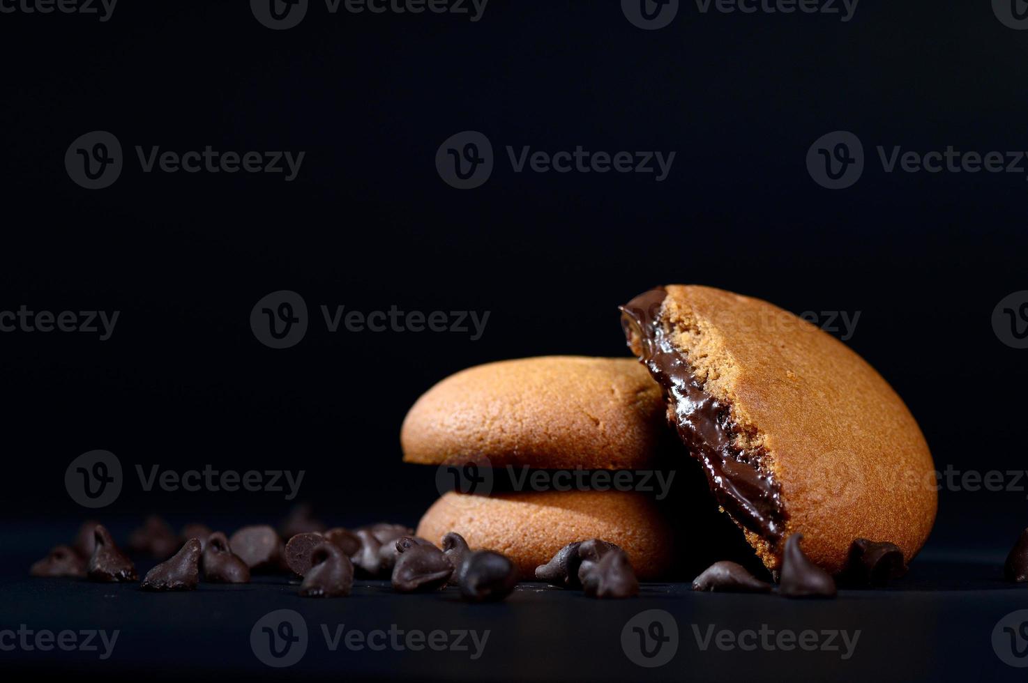 galletas rellenas de crema de chocolate. galletas de crema de chocolate. Galletas de chocolate marrón con relleno de crema sobre fondo negro. foto