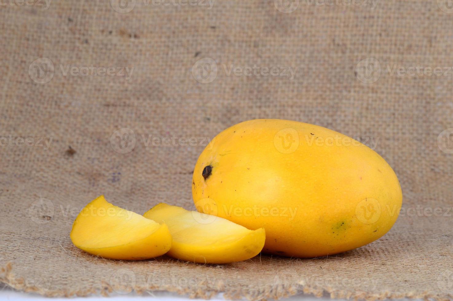 Fruta de mango con rodaja sobre fondo de tela de saco foto