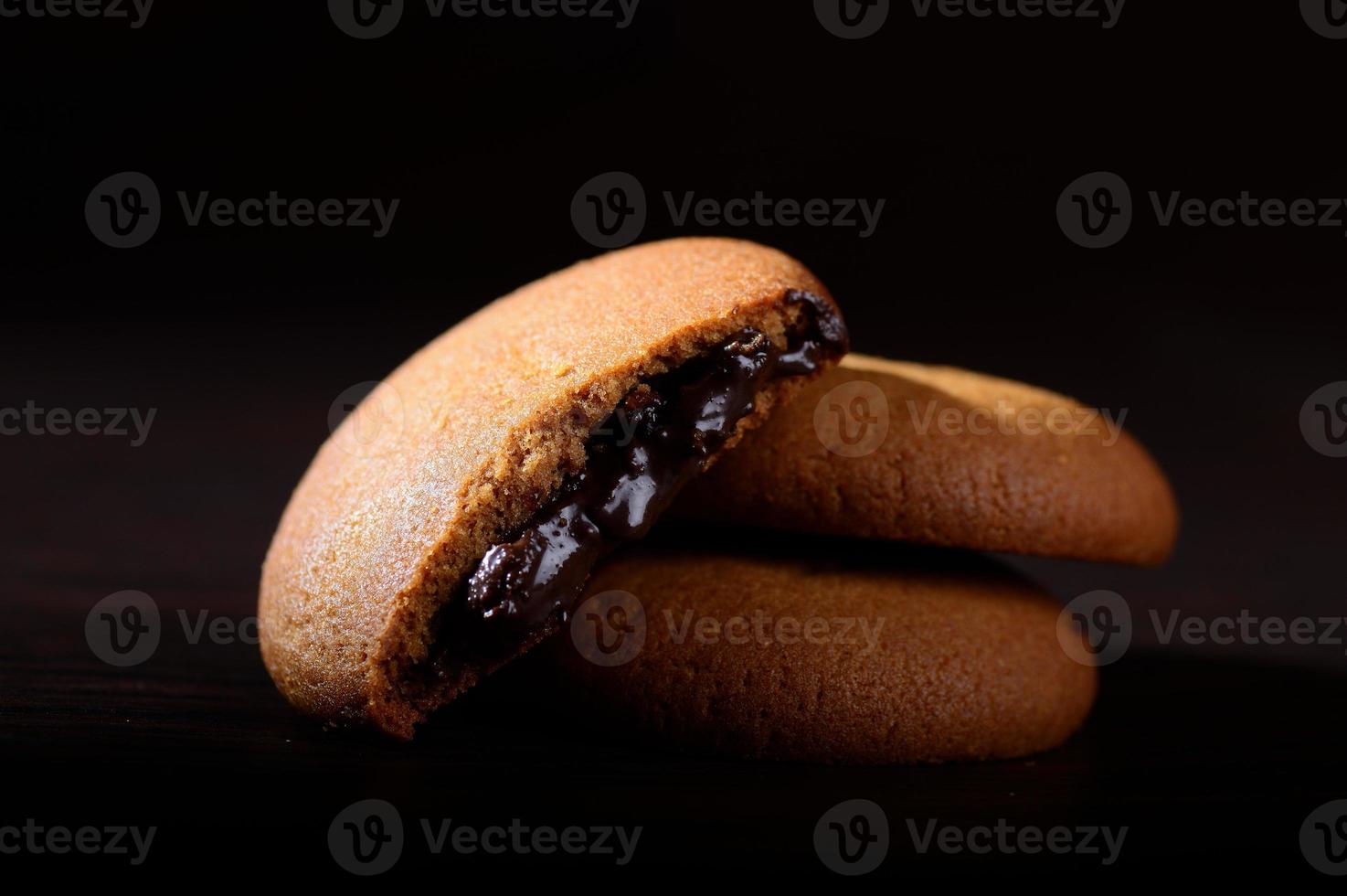 Biscuits filled with chocolate cream. Chocolate cream cookies. brown chocolate biscuits with cream filling on black background. photo