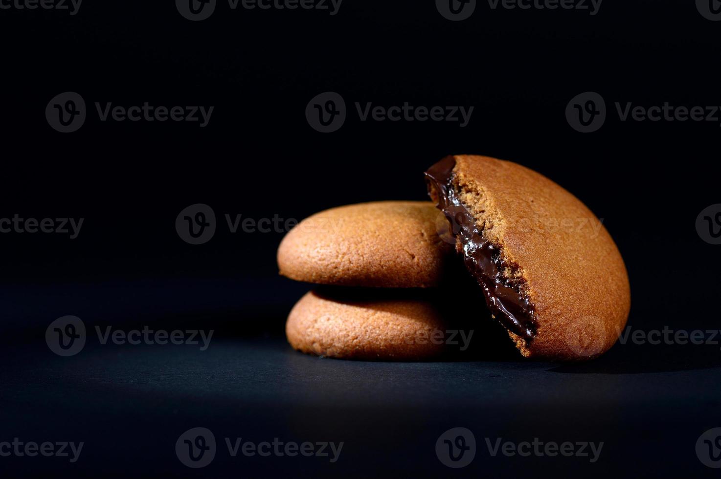 Biscuits filled with chocolate cream. Chocolate cream cookies. brown chocolate biscuits with cream filling on black background. photo