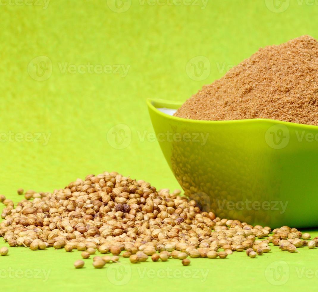 Coriander seeds and Powdered coriander in green container on green background photo