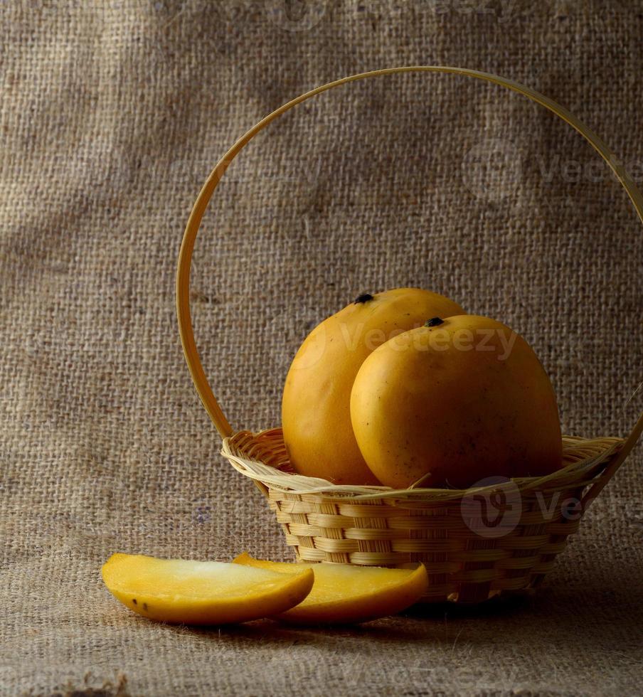 Fruta de mango en la canasta sobre fondo de tela de saco foto