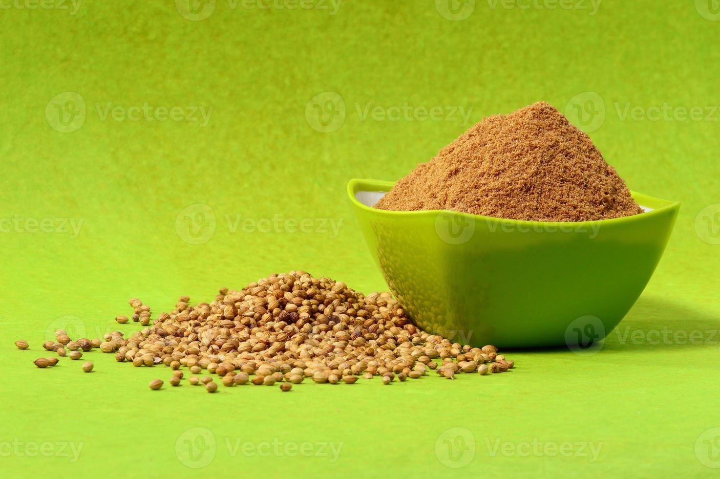 Coriander seeds and Powdered coriander in green container on green background photo