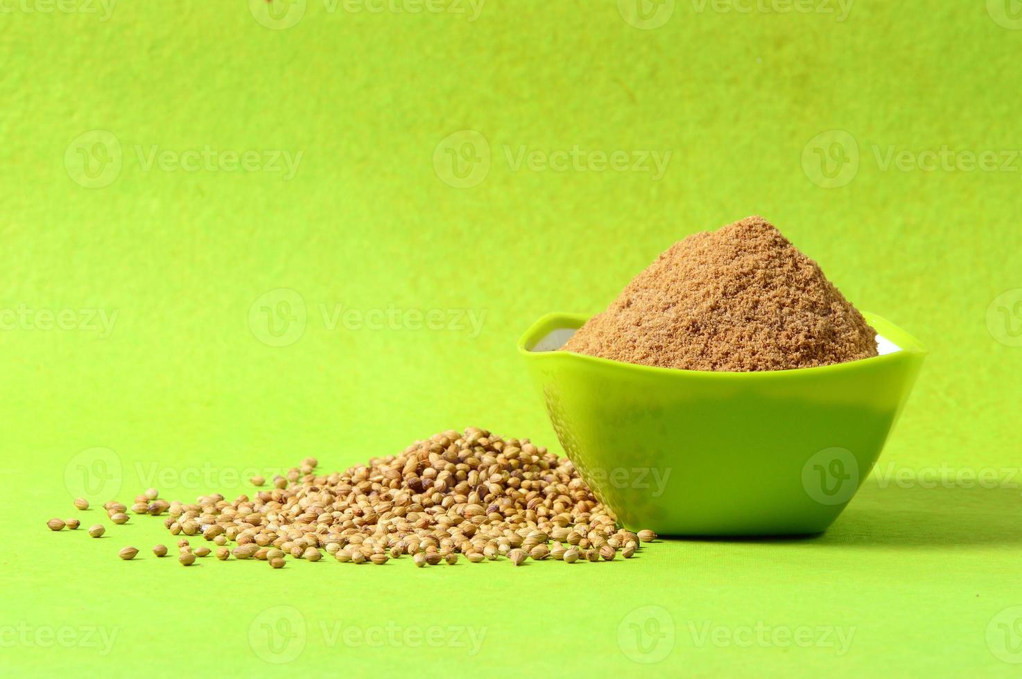 Coriander seeds and Powdered coriander in green container on green background photo