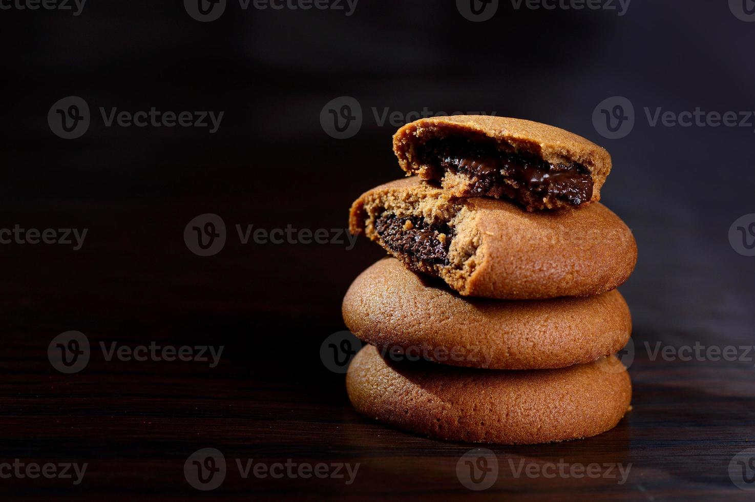 galletas rellenas de crema de chocolate. galletas de crema de chocolate. Galletas de chocolate marrón con relleno de crema sobre fondo negro. foto