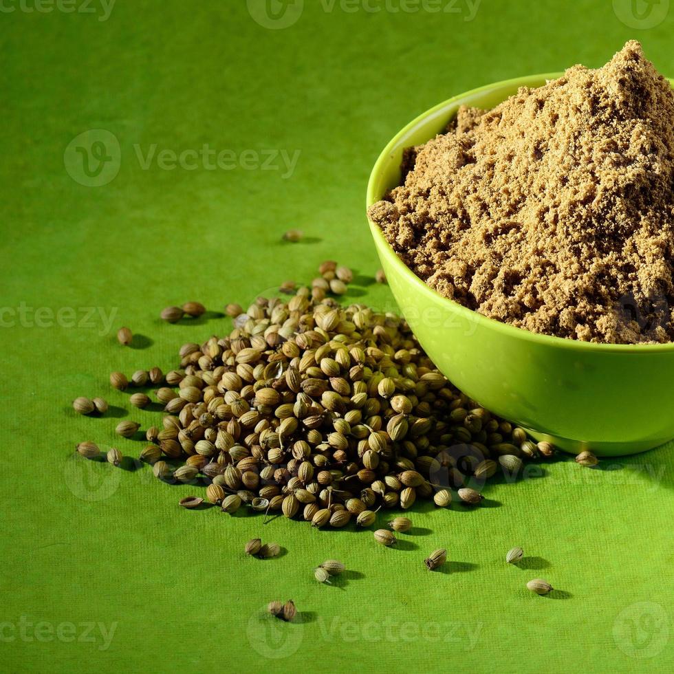 Coriander seeds and Powdered coriander in green container on green background photo