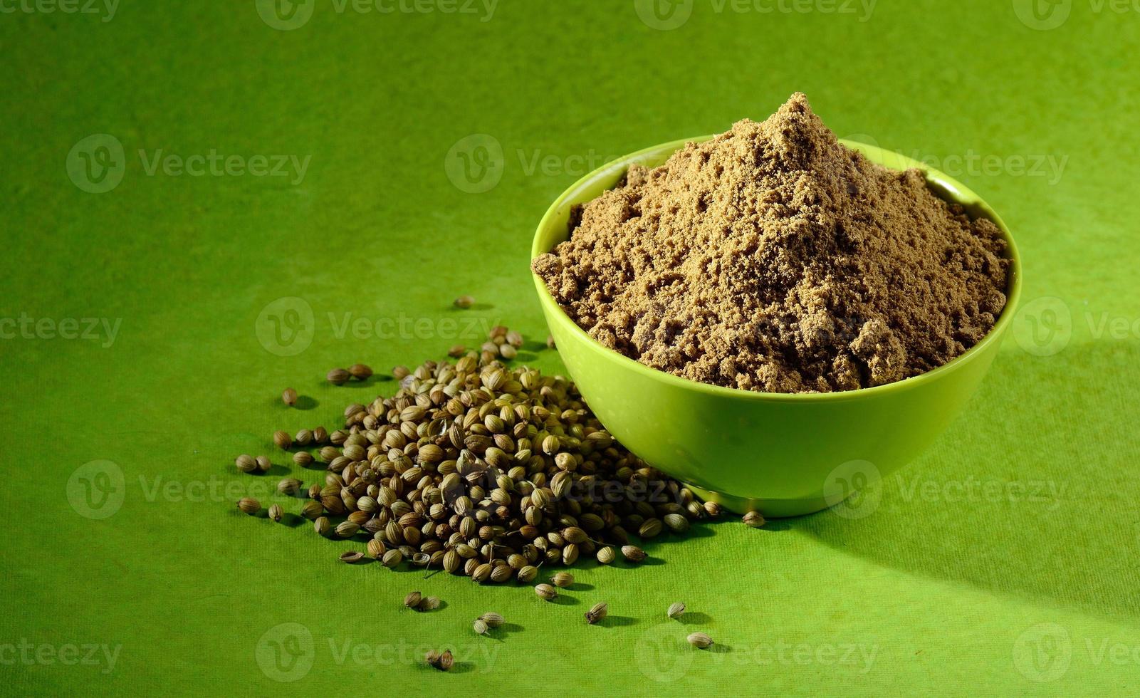 Coriander seeds and Powdered coriander in green container on green background photo