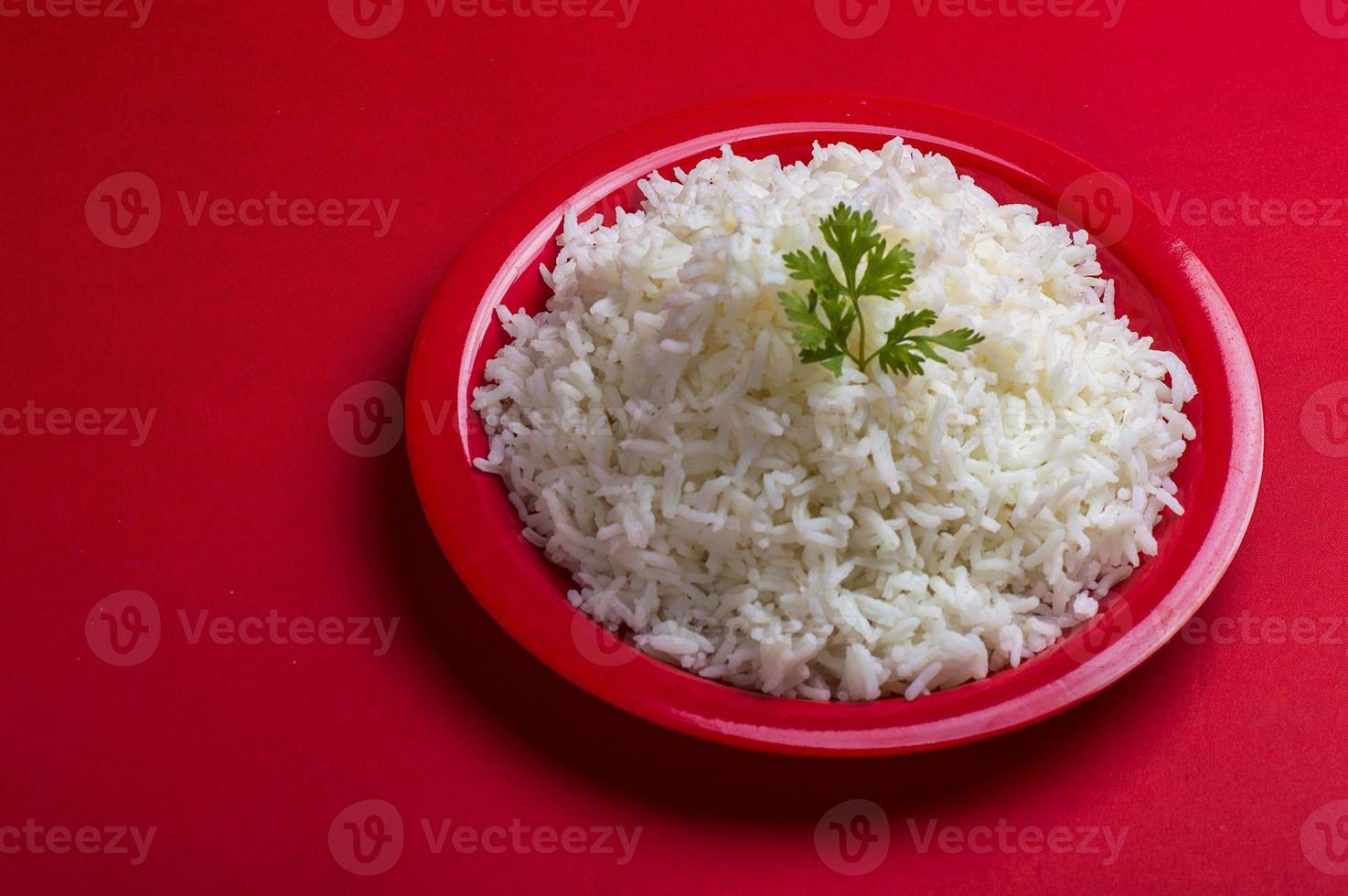 Arroz basmati blanco liso cocido en una placa roja sobre fondo rojo. foto