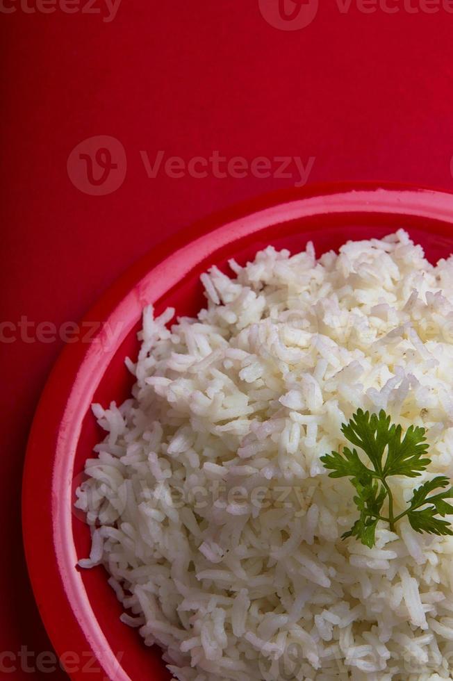 Arroz basmati blanco liso cocido en una placa roja sobre fondo rojo. foto