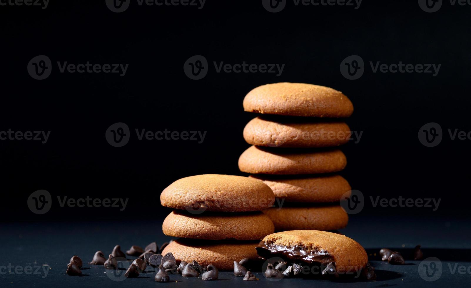 BISCUITS - Stack of delicious cream biscuits filled with chocolate cream on black background photo