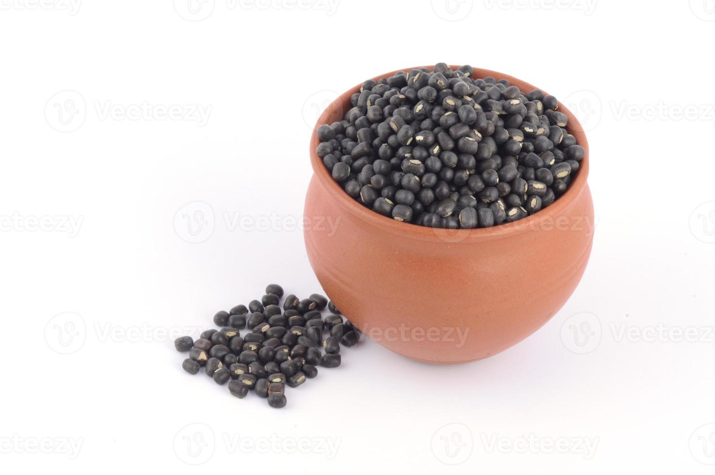 urad dal, gramo negro, vigna mungo en olla de barro sobre fondo blanco. foto