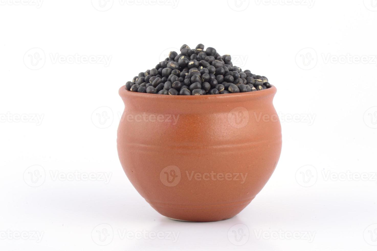 urad dal, gramo negro, vigna mungo en olla de barro sobre fondo blanco. foto