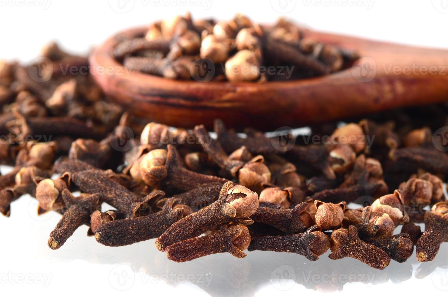 Cloves spice and wooden spoon close-up food background. Isolated on white background photo