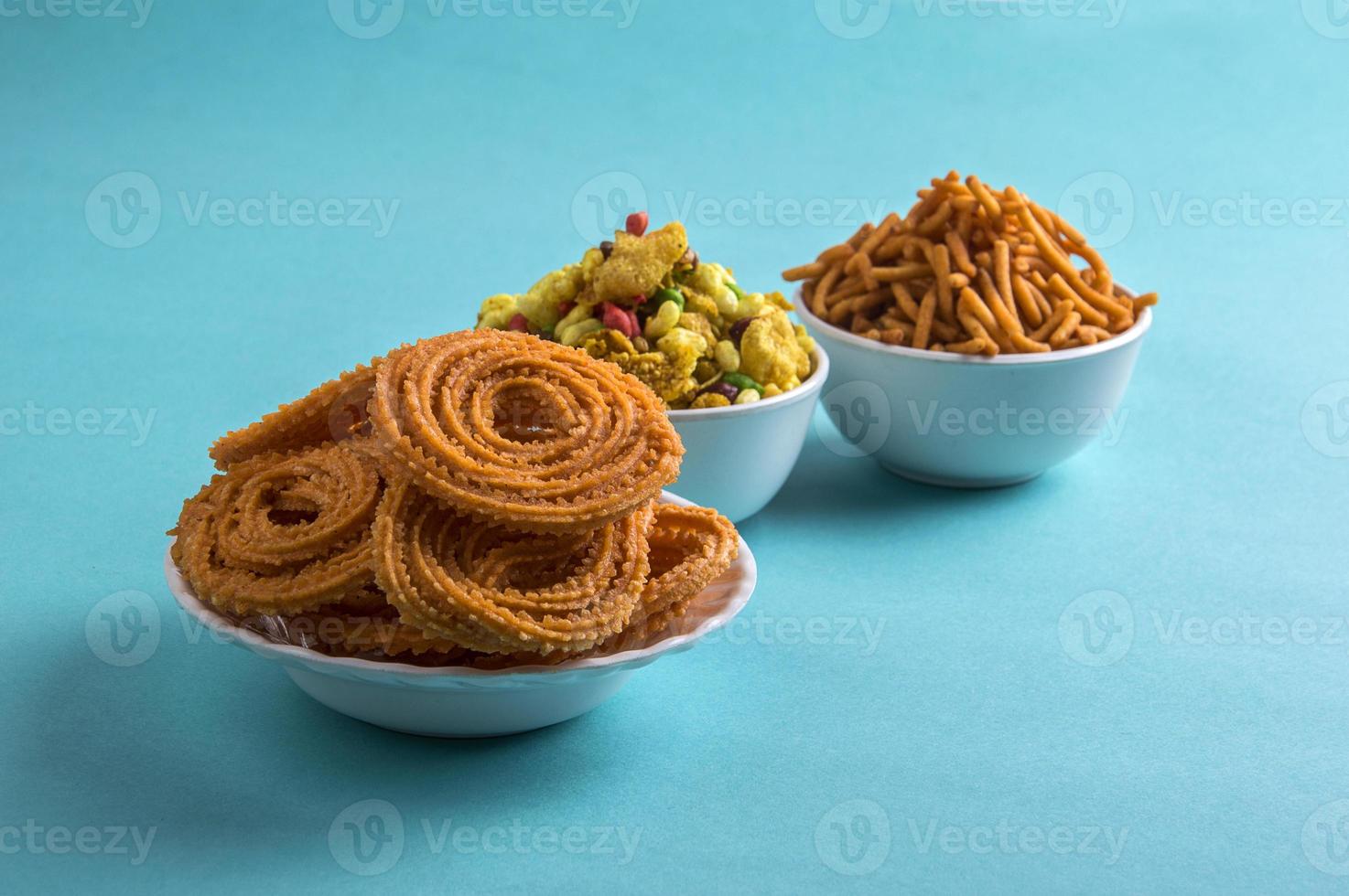 Bocadillo indio chakli, chakali o murukku y harina de gramo besan sev y chivada o chiwada sobre fondo azul. comida diwali foto