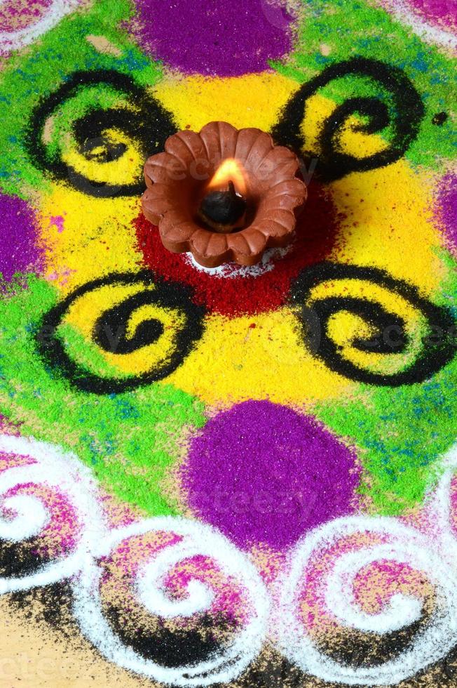 Lámparas de arcilla diya encendidas durante la celebración de Diwali, rangoli en segundo plano. foto