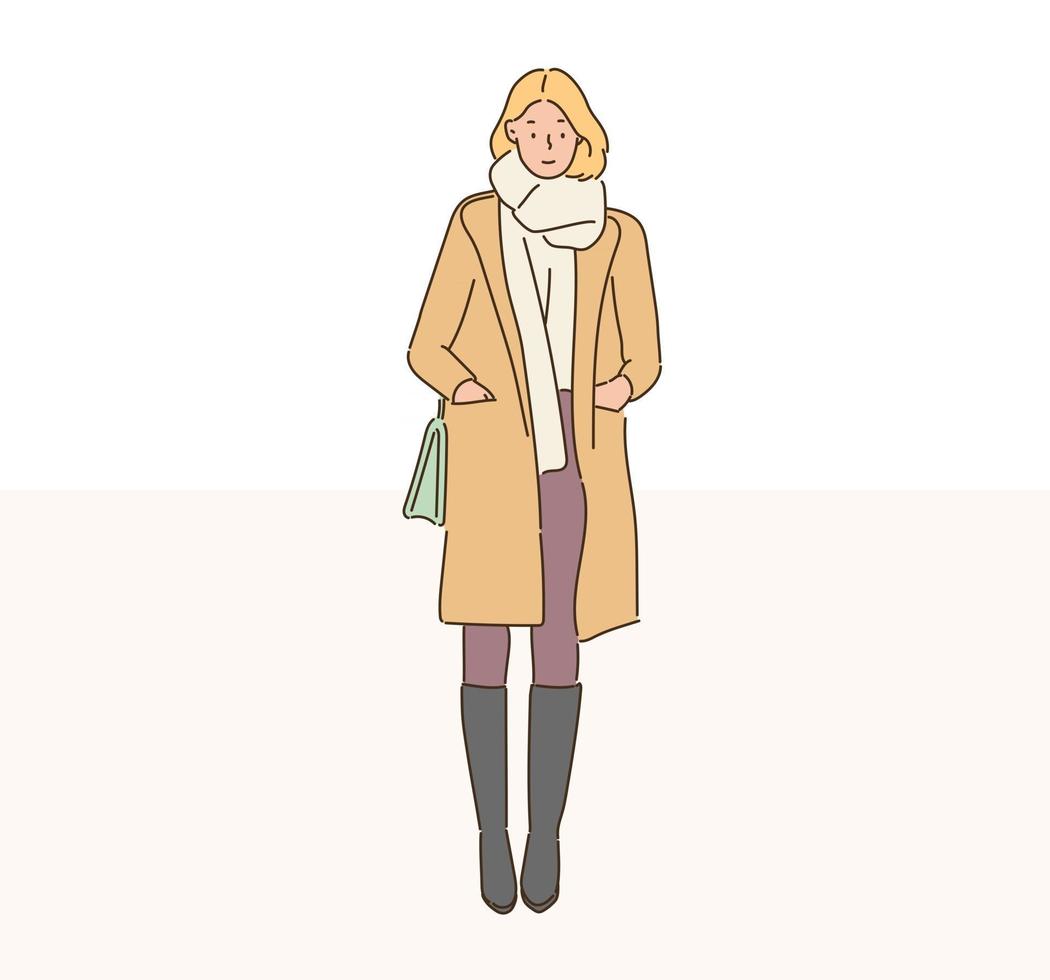 A fashionable woman is standing in a long coat. hand drawn style vector design illustrations.