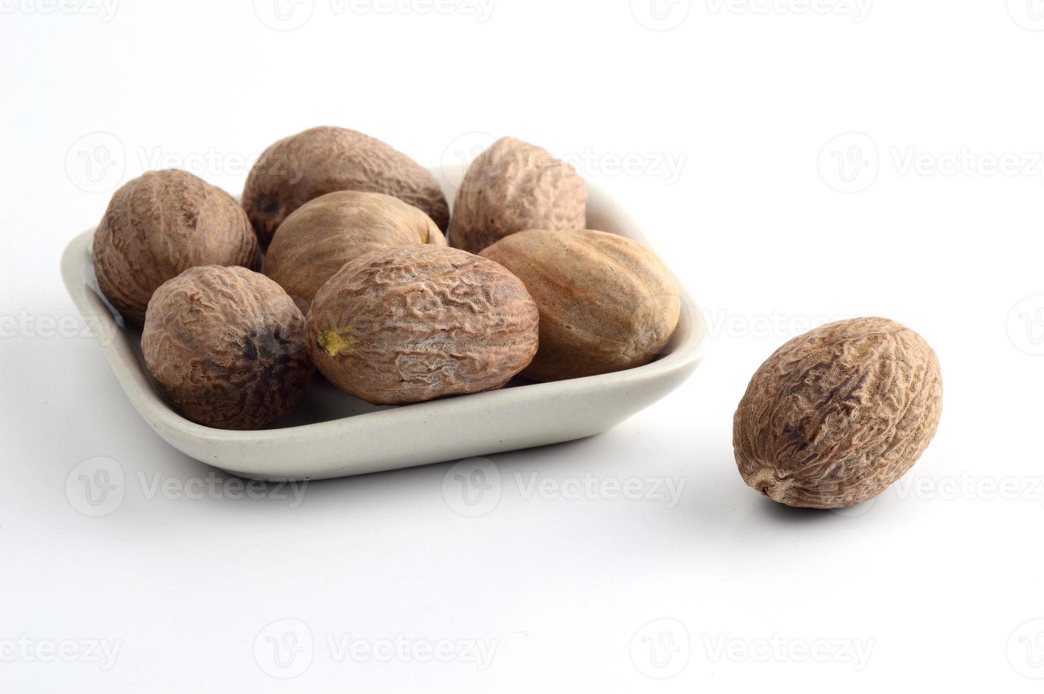 Nutmeg in white plate isolated on white background photo