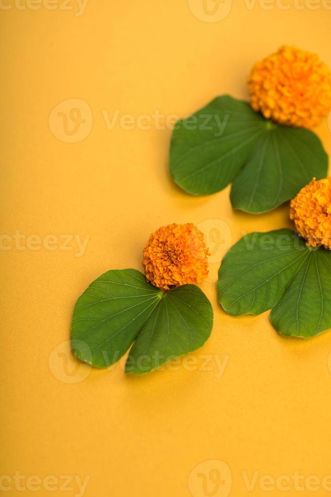 Indian Festival Dussehra, showing golden leaf Bauhinia racemosa and marigold flowers on a yellow background. photo