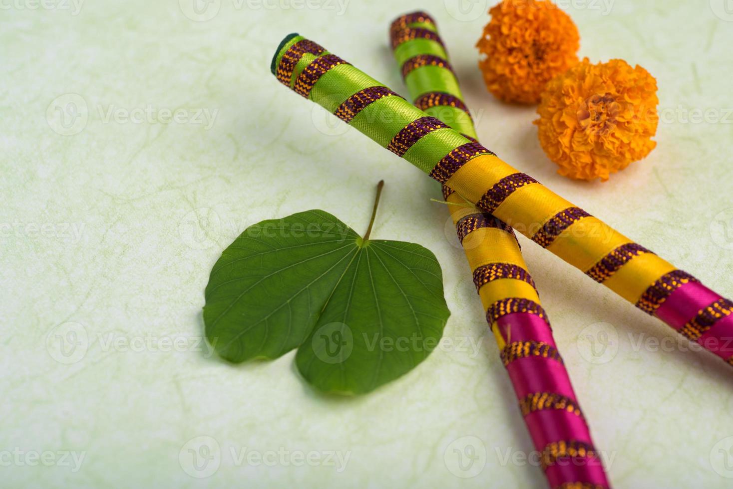 festival indio dussehra, mostrando hojas doradas de bauhinia racemosa y flores de caléndula con palitos de dandiya. foto