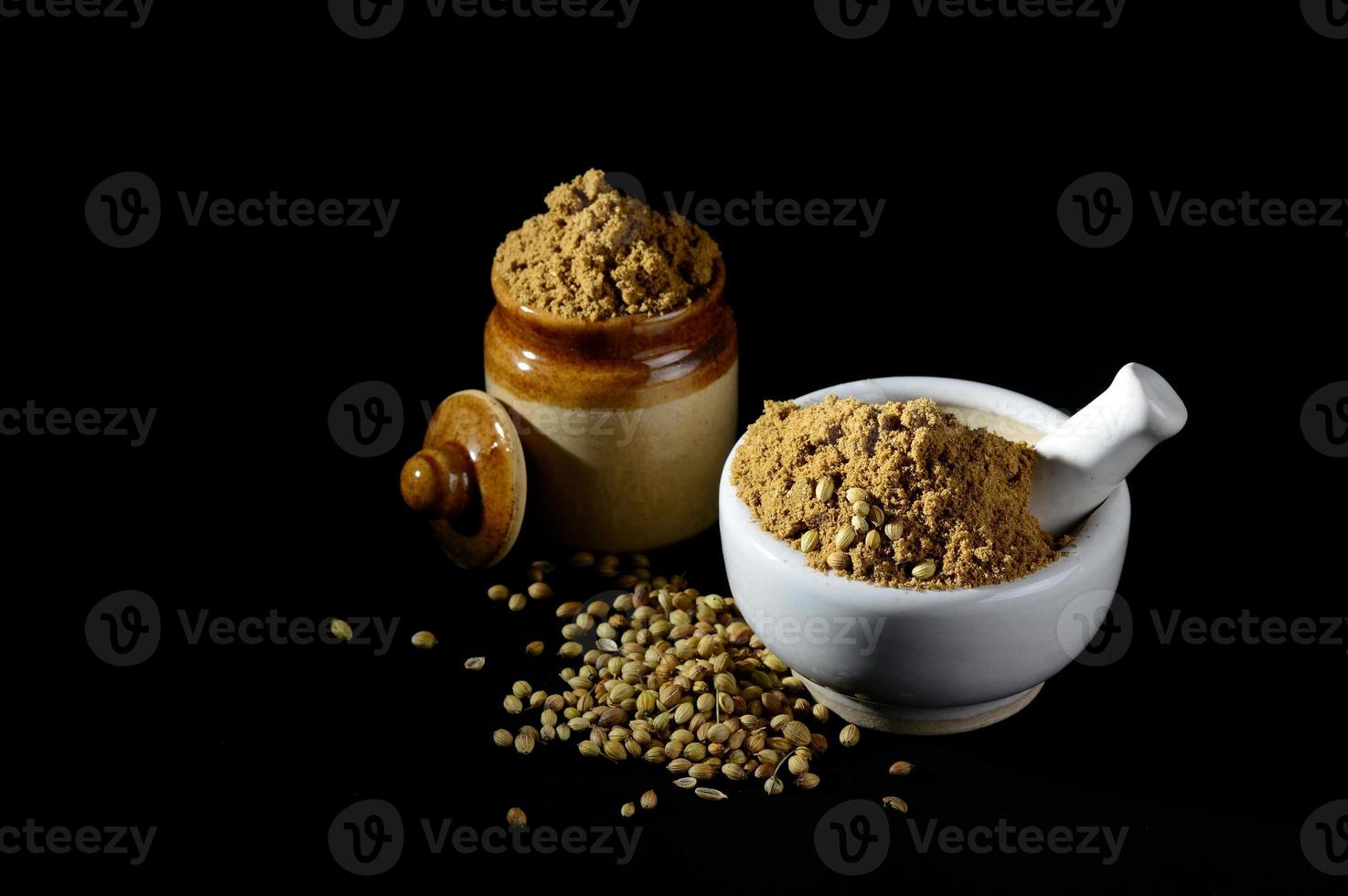 mortar and pestle with Coriander Powder and seeds on black background. photo
