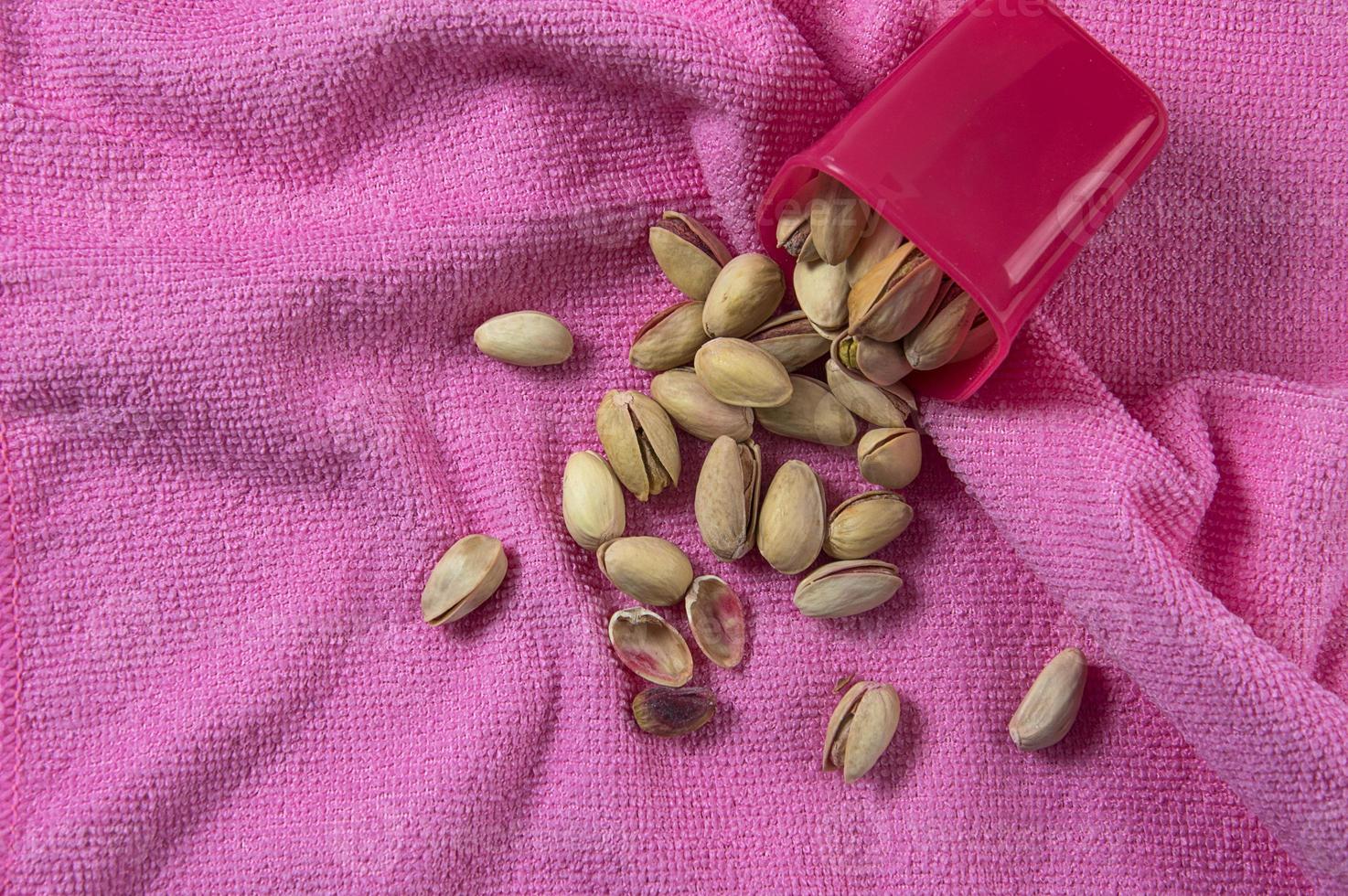 Pistachios in container on pink background photo