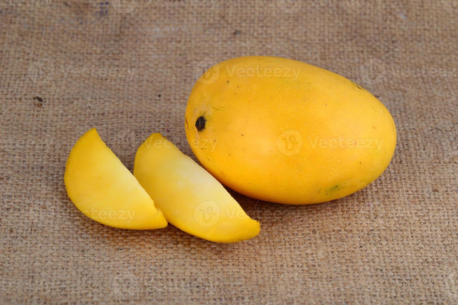 Fruta de mango con rodaja sobre fondo de tela de saco foto