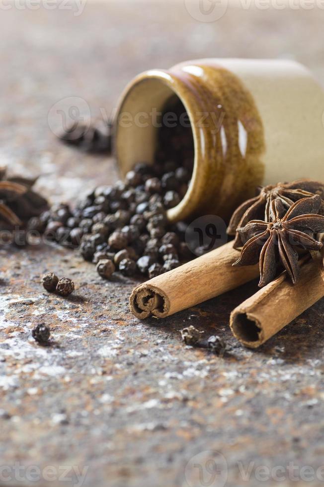 especias y hierbas. ingredientes de la comida y la cocina. palitos de canela, estrellas de anís, granos de pimienta negra sobre fondo de textura foto