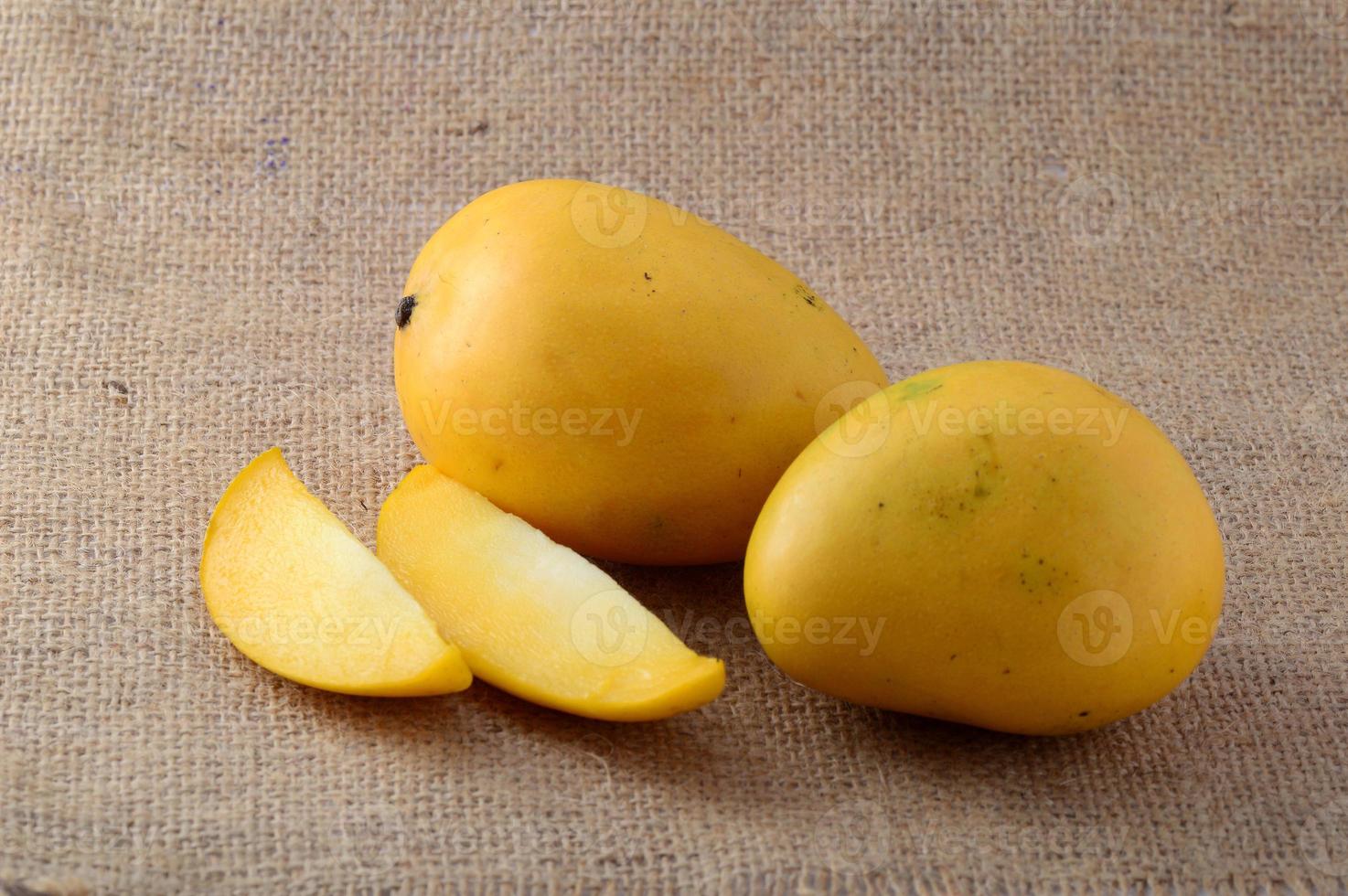 Fruta de mango con rodaja sobre fondo de tela de saco foto