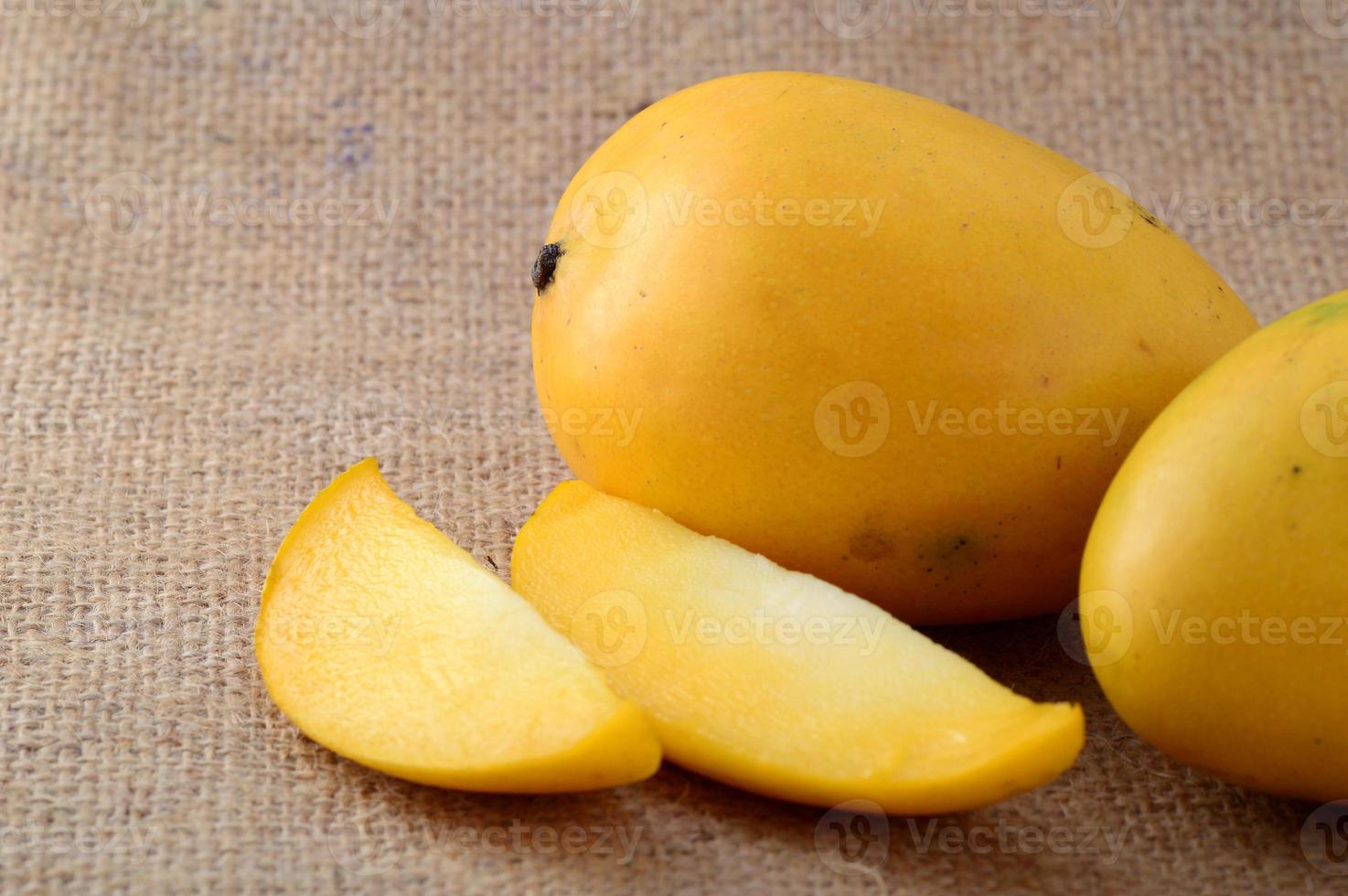 Fruta de mango con rodaja sobre fondo de tela de saco foto