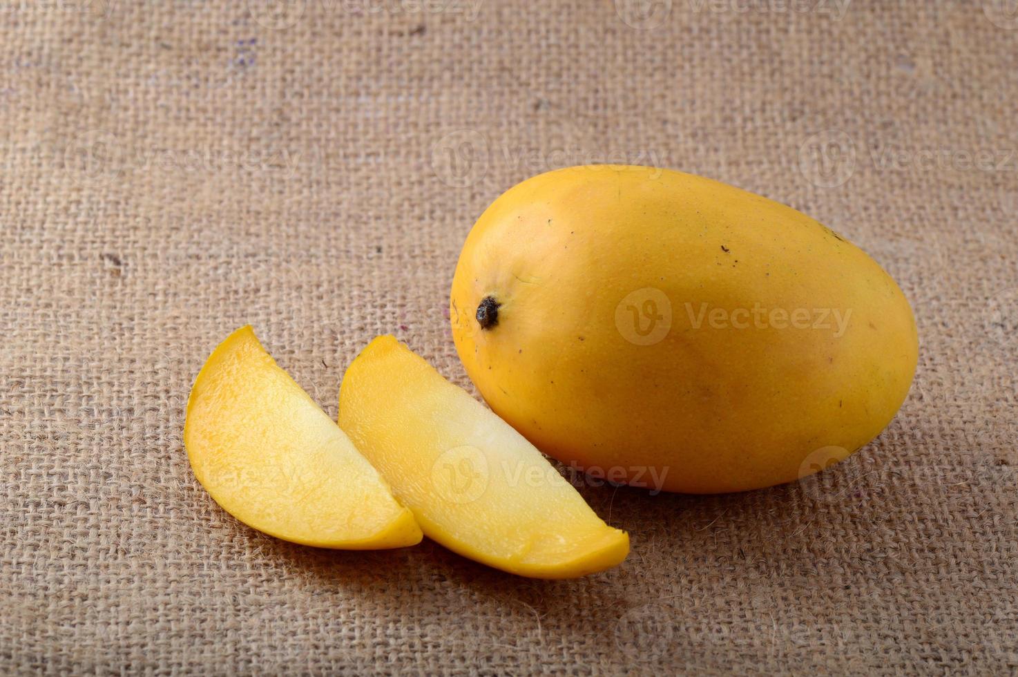 Fruta de mango con rodaja sobre fondo de tela de saco foto