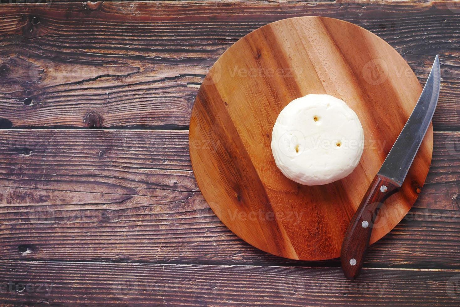 top view of round shape fresh cheese on chopping board photo