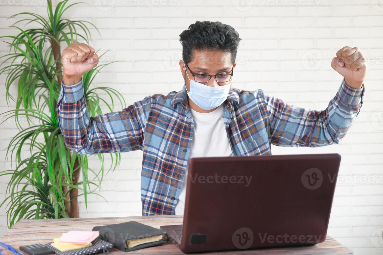 alegre, joven, en, mascarilla, trabajando, en, computadora portátil foto