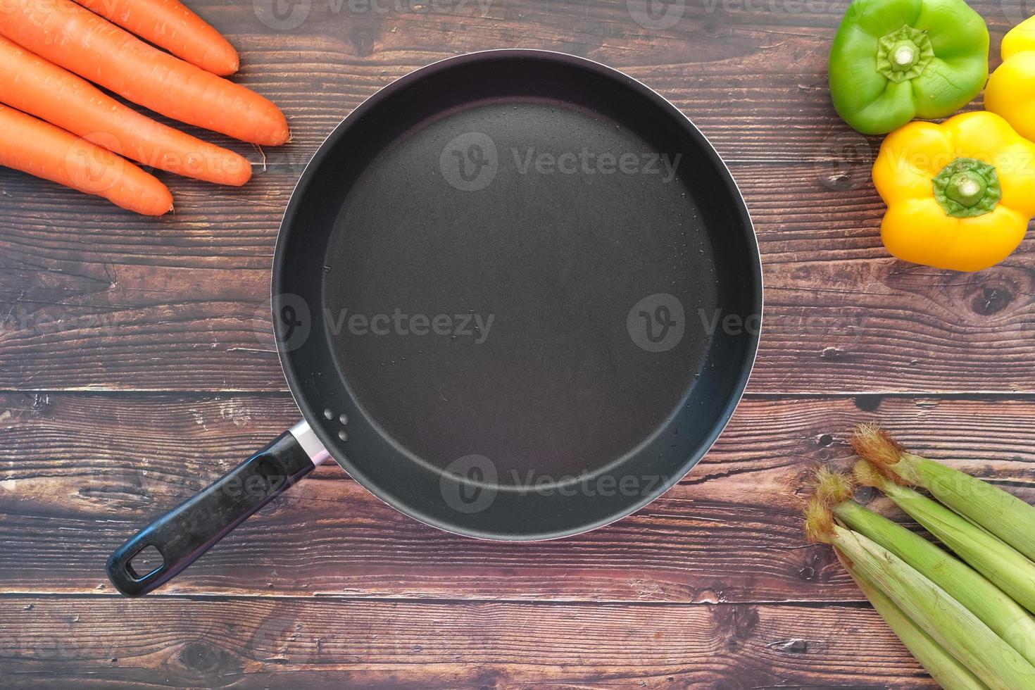 empty frying pan and vegetables on table photo
