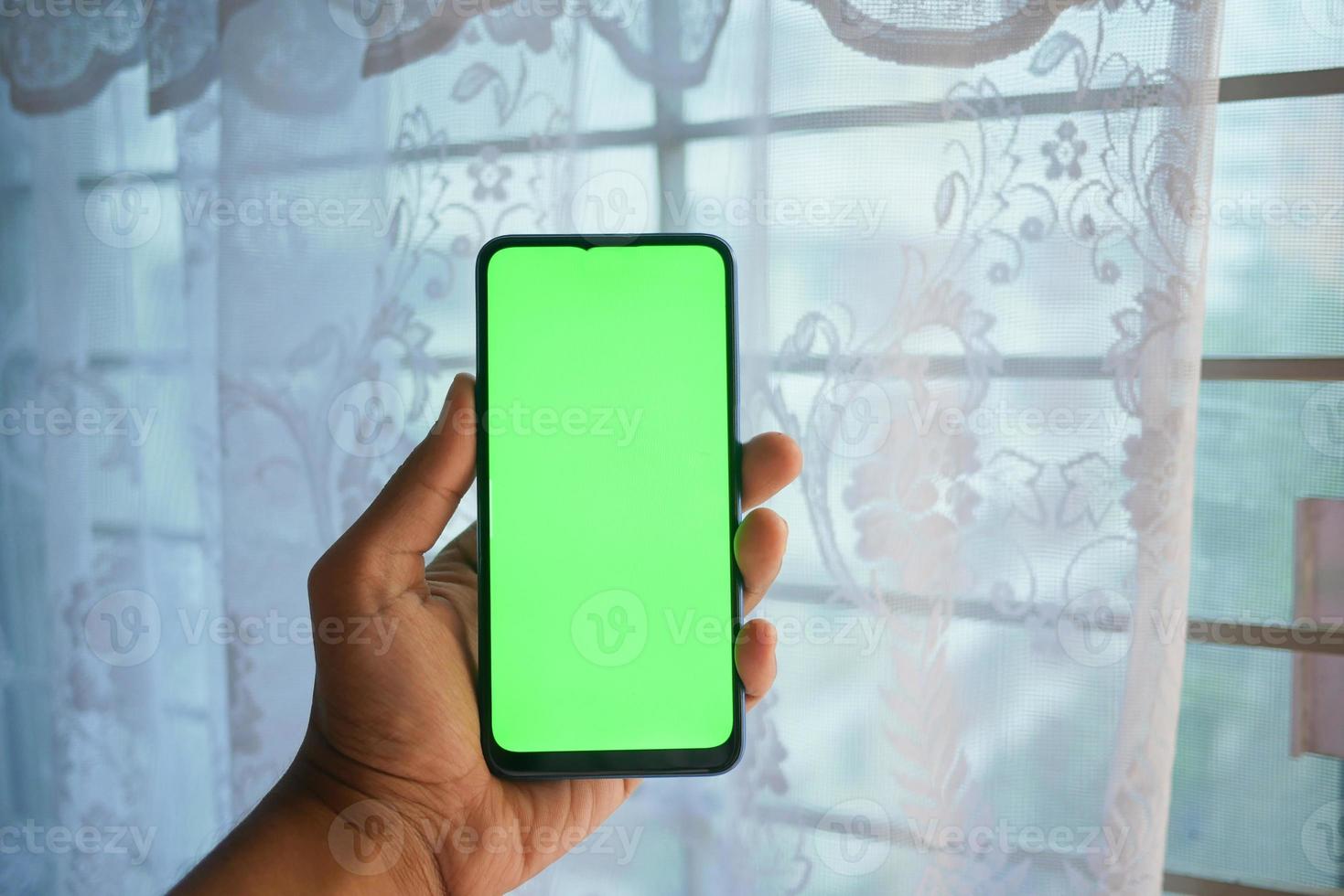 Cerca de la mano del hombre joven con un teléfono inteligente con pantalla verde foto