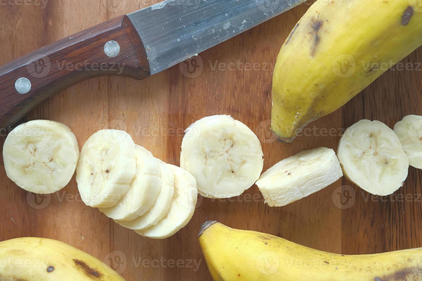 Cerca de una rodaja de plátano fresco y un cuchillo de cocina en la mesa foto