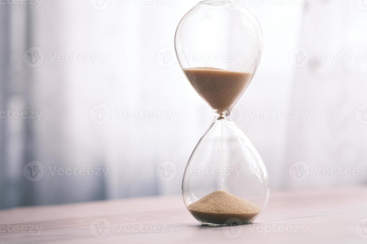 hourglass on table, sand flowing through the bulb of sandglass photo