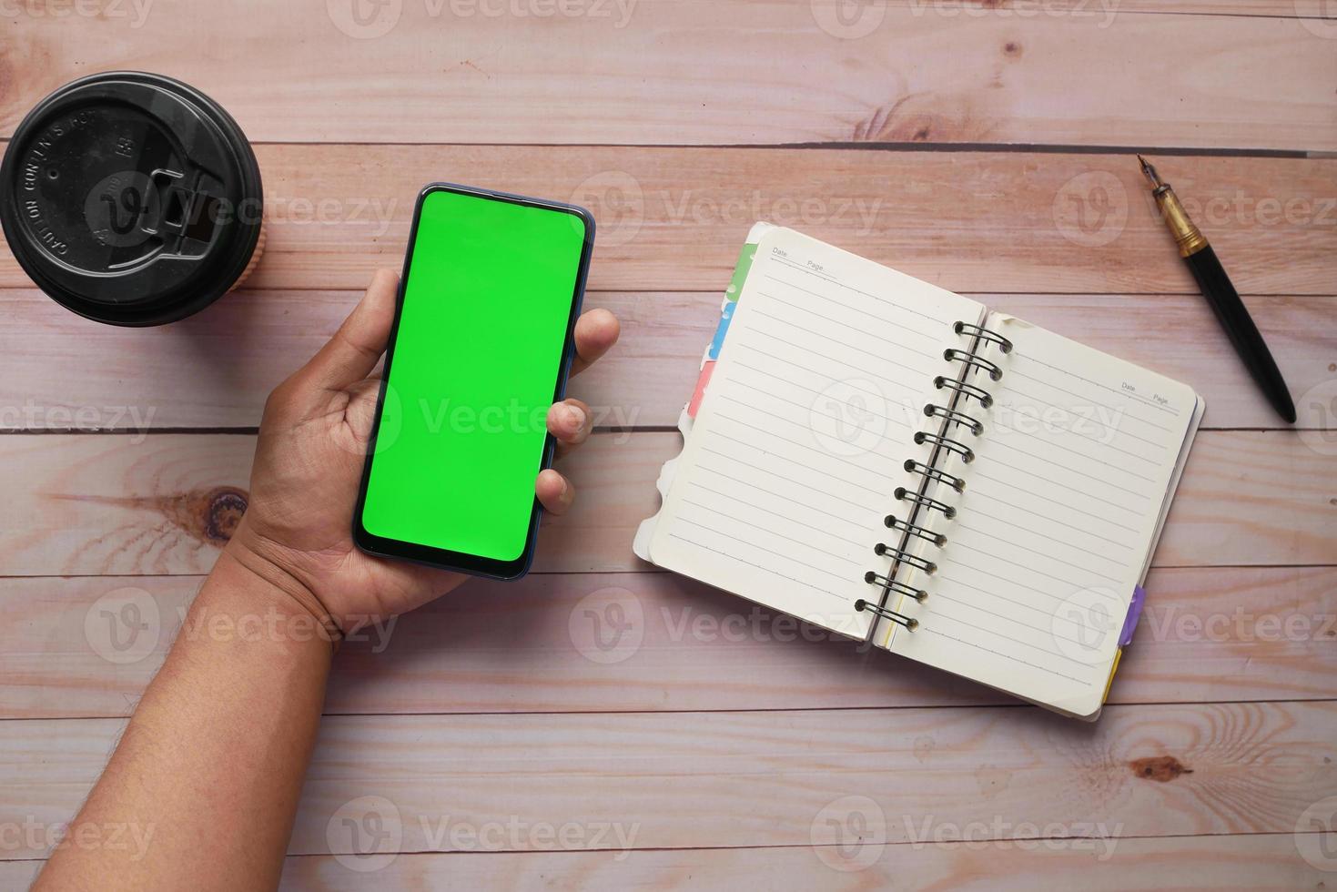 top view of man hand using smart phone on office desk photo