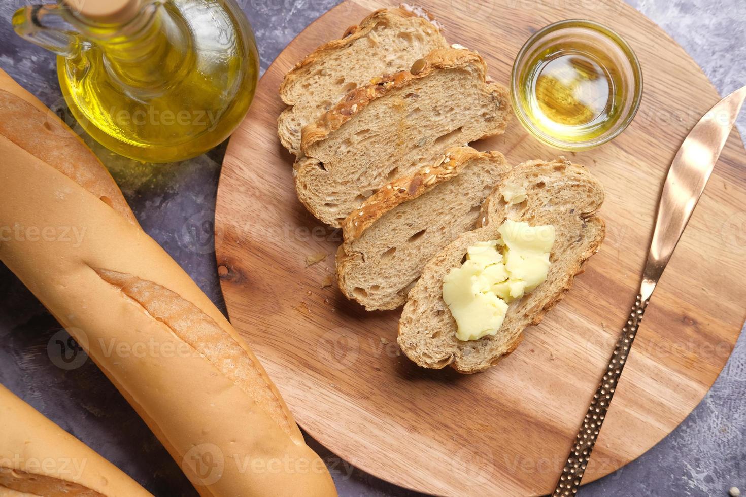 Rebanada de mantequilla y pan integral sobre una tabla de cortar foto