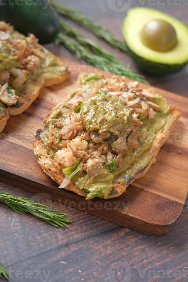 tuna fish and avocado on slice of a brown bread on table photo